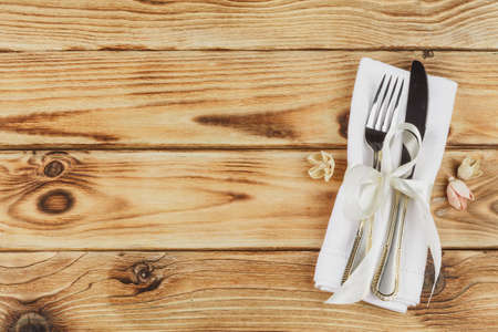 Cutlery wrapped in a napkin on a wooden tableの写真素材