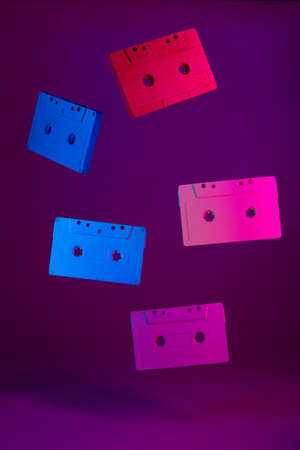 Colored audio cassettes hanging in the air against purple backgroundの写真素材