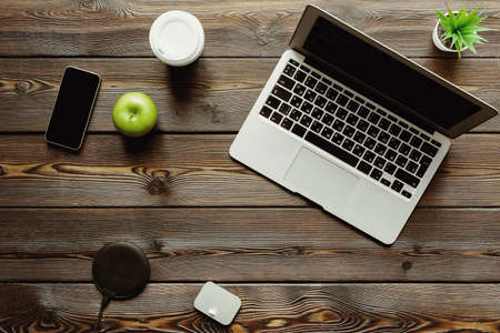 Office desk with laptop computer, supplies and green apple, top viewの写真素材