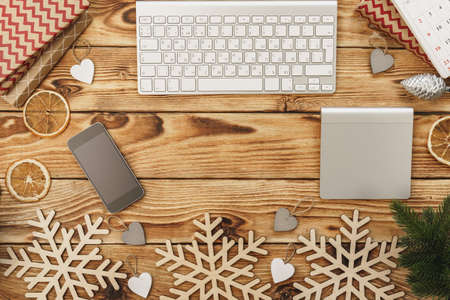 Wooden table with office equipment and stationery surrounded with new year festive decor, view from aboveの写真素材