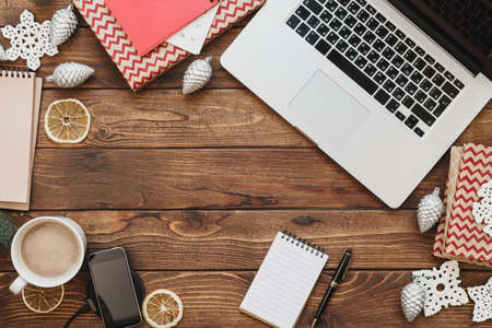 Top view of a wooden desktop with computer with office supplies and christmas decorationsの写真素材