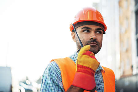 Young construction worker in uniform using walkie talkie on siteの写真素材