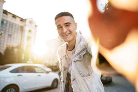 Portrait of young man taking a selfie while out on the city street, close upの写真素材