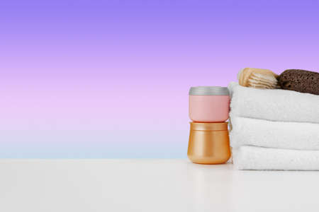 Pile of towels, bottles with shampoo on white tableの写真素材