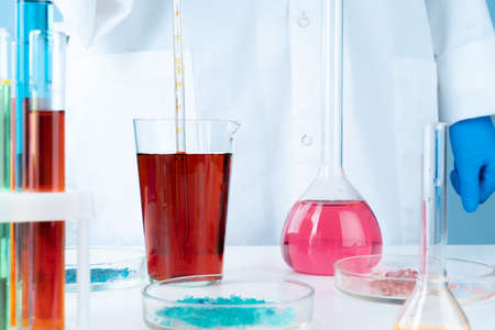Manipulations with laboratory glass chemical containers on table