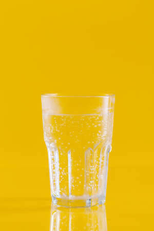 Glass of water on yellow background. Healthy lifestyleの写真素材