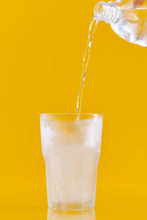 Cold water pouring from a bottle into a glassの写真素材