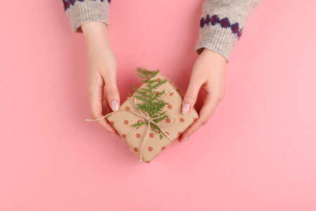 Top view of woman hands holding gift box on pink backgroundの写真素材