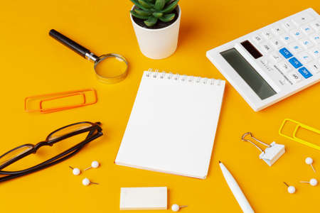 Stylish messy yellow desk top with various stationery top viewの写真素材