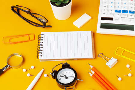 Stylish messy yellow desk top with various stationery top viewの写真素材