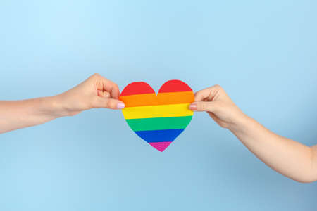 Gay love. Human hand holding a rainbow paper heartの写真素材