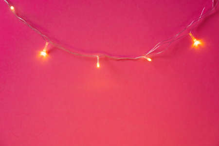 Illuminated garland lights on bright pink backgroundの写真素材