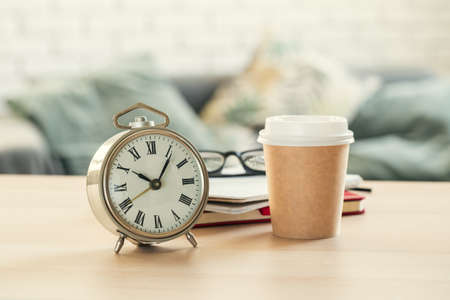 Classic vintage alarm clock and coffee cup on wooden backgroundの写真素材