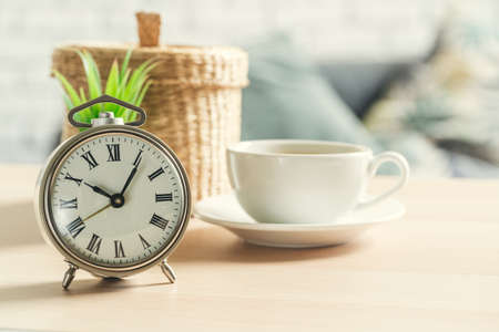 Classic vintage alarm clock and coffee cup on wooden backgroundの写真素材
