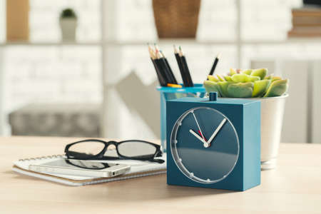 Old-fashioned alarm clock and house plant on wooden table