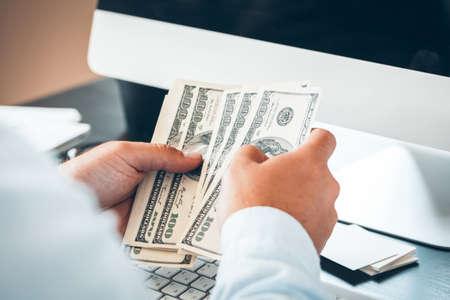 Caucasian hands counting dollar banknotesの写真素材