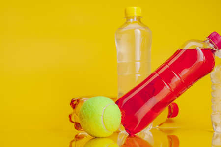 Plastic bottle full of drink on a bright yellow backgroundの写真素材