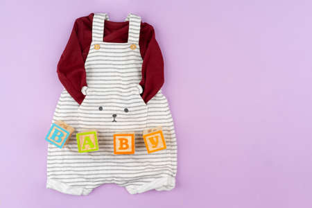 Baby girl clothes on lilac pastel backgroundの写真素材
