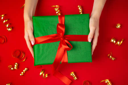 Female hands holding present on a red background