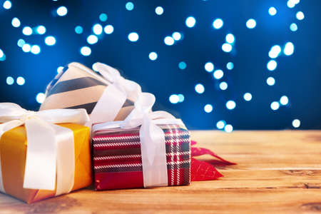 Small christmas gift boxes on wooden table against bokeh lights background