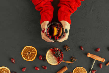 Womans hands in warm sweater holding a cup of mulled wineの写真素材
