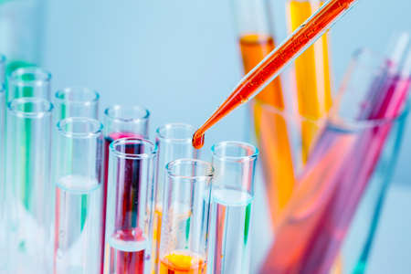 Laboratory test tubes with red and yellow liquids on light blue background