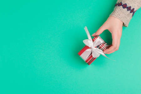 Woman hands holding gift box on green backgroundの写真素材