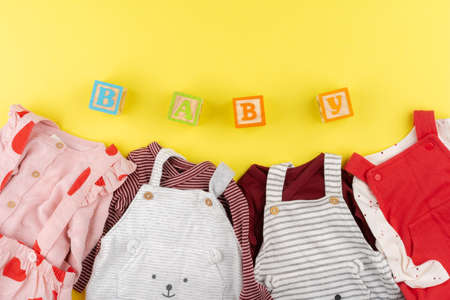 Top view of baby girl clothes on yellow backgroundの写真素材