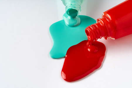 Nail polishes spilled out of bottles on white backgroundの写真素材
