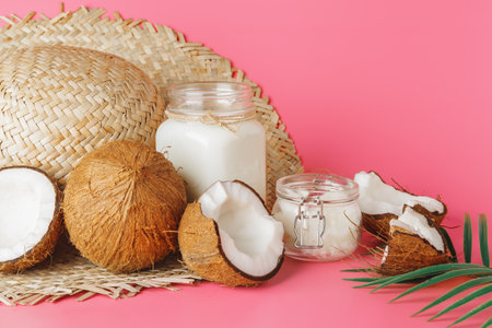 Cracked coco and coconut milk in glass on bright pink background