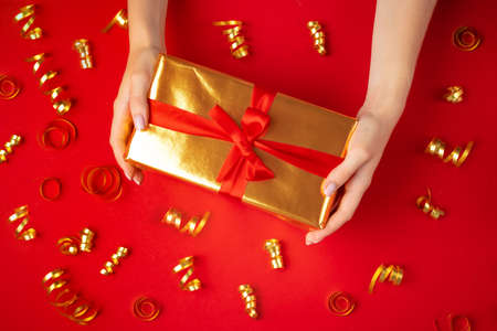Female hands holding present on a red backgroundの写真素材