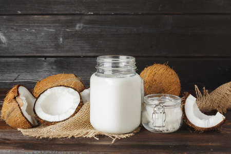 Broken coconut and coconut milk on black wooden backgroundの写真素材