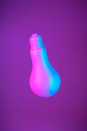 Lightbulb suspended in air on a bright purple backgroundの写真素材