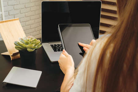 Woman using digital tablet sitting at a table in an officeの写真素材
