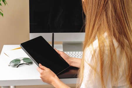 Woman using digital tablet sitting at a table in an officeの写真素材