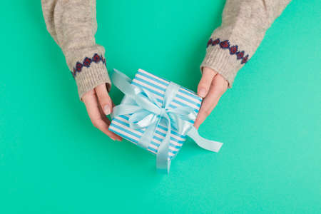 Woman hands holding gift box on green backgroundの写真素材
