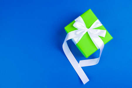 Flat lay of gift box decorated with bow on blue backgroundの写真素材