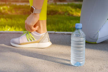 Woman runner tying her shoes laces preparing for a morning run