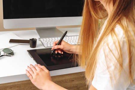 Woman designer working in office and using a graphic tablet