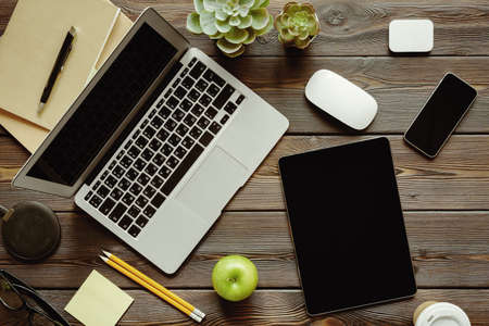 Office desk with laptop computer, supplies and green apple, top viewの写真素材