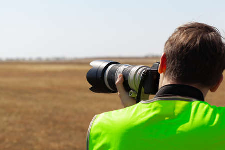 Man in yellow vest does plane spotting at the airportの写真素材