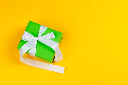 Decorated colored present on yellow background flatlay
