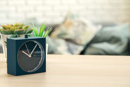 Old-fashioned alarm clock and house plant on wooden table