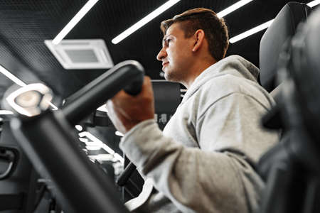 Young fit bodybuilder man doing arms workout training in the gym on machine