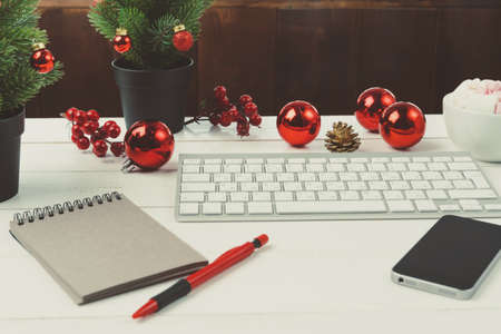 Open notepad and computer on table with christmas decor