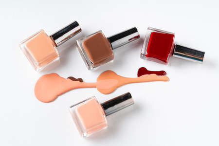 Bright colored nail polish bottles with drippings on white backgroundの写真素材