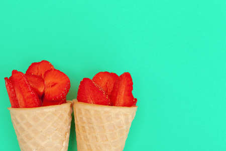 Waffle cone with fresh strawberries on vibrant backgroundの写真素材