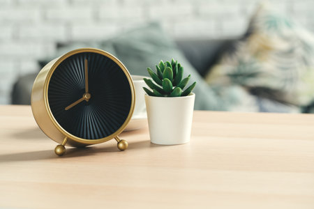 Old-fashioned alarm clock and house plant on wooden tableの写真素材
