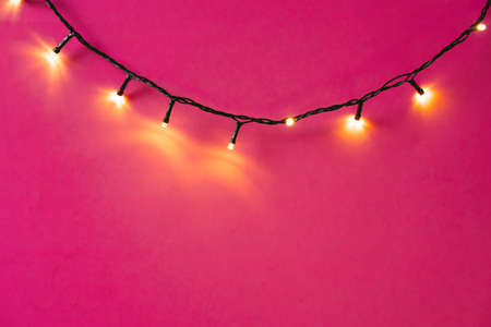 Illuminated garland lights on bright pink backgroundの写真素材