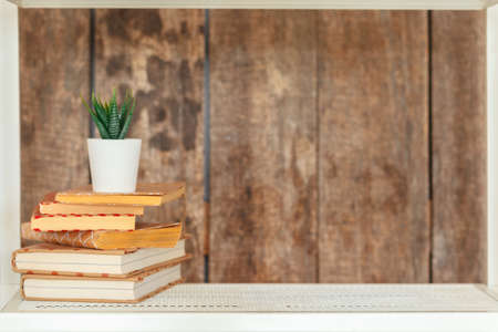 Stylish white bookshelf against grunge wooden wallの写真素材